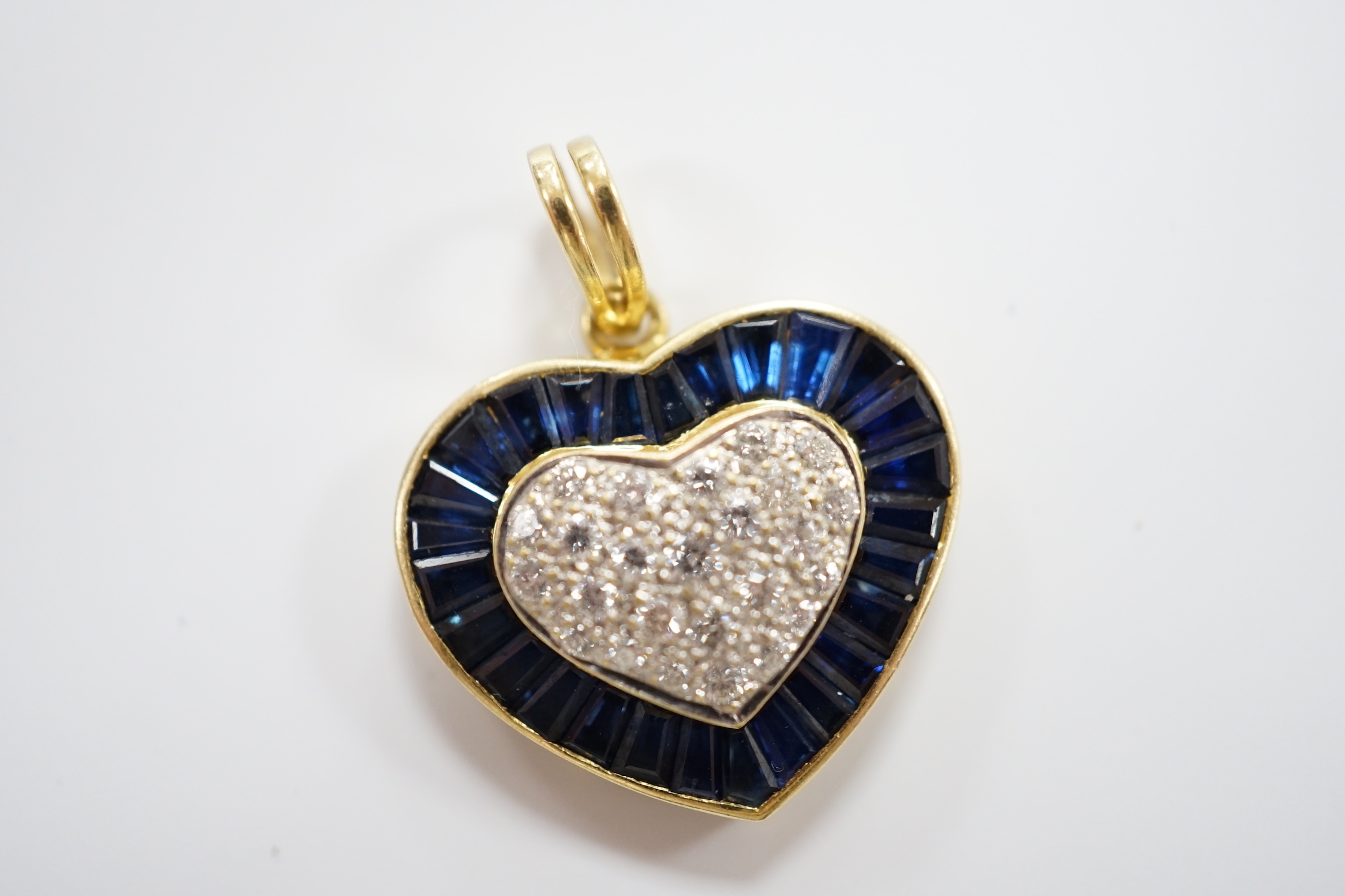 A modern 18k, pave set sapphire and diamond heart shaped pendant, overall 25mm, gross weight 4.9 grams.